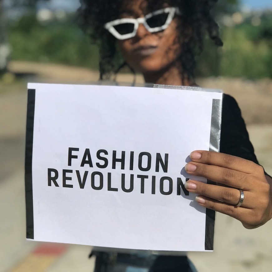 Mulher segurando placa com a mensagem Fashion Revolution